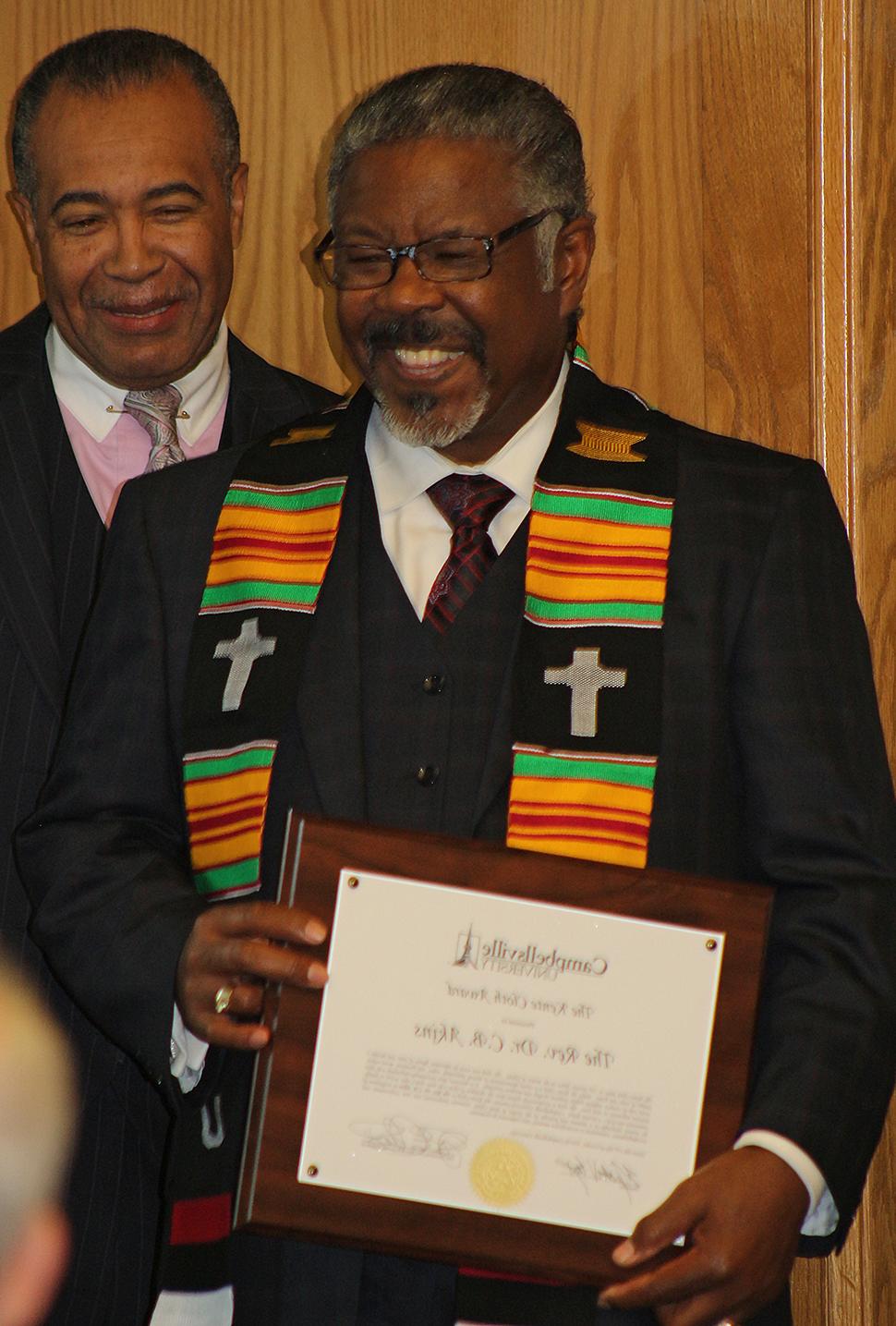 Dr. C.B. Akins, left, upon receiving the Kente  Cloth Award. To the right is Dr. Joseph Owens,  chair of CU's Board of Trustees, who helped present  the award. (Campbellsville University Photo by  Drew Tucker)